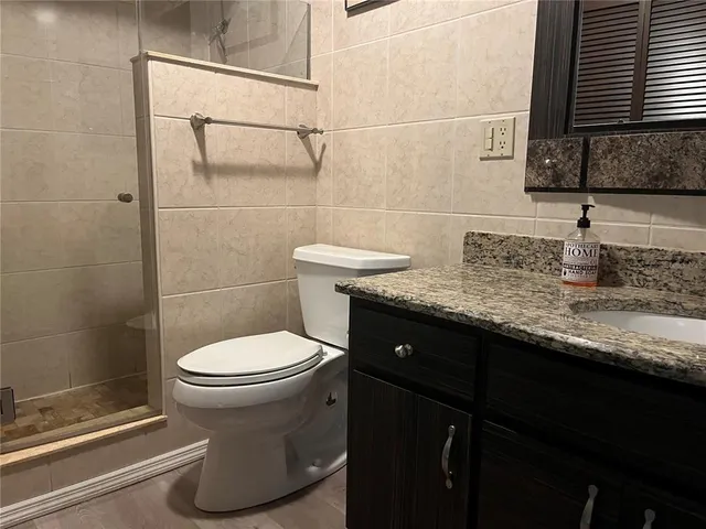 a bathroom with a granite countertop toilet sink and mirror