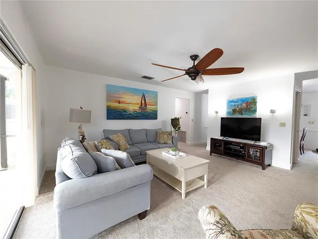 a living room with furniture a ceiling fan and a window