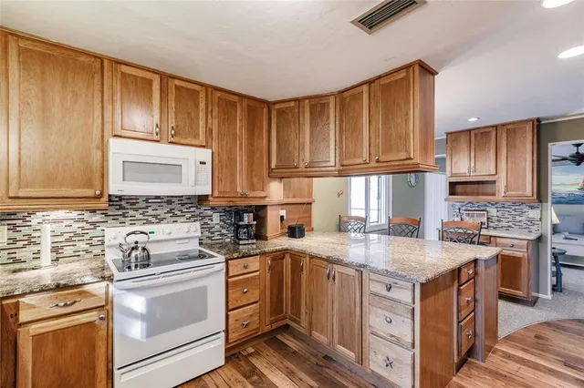 a kitchen with kitchen island granite countertop a sink stove and cabinets