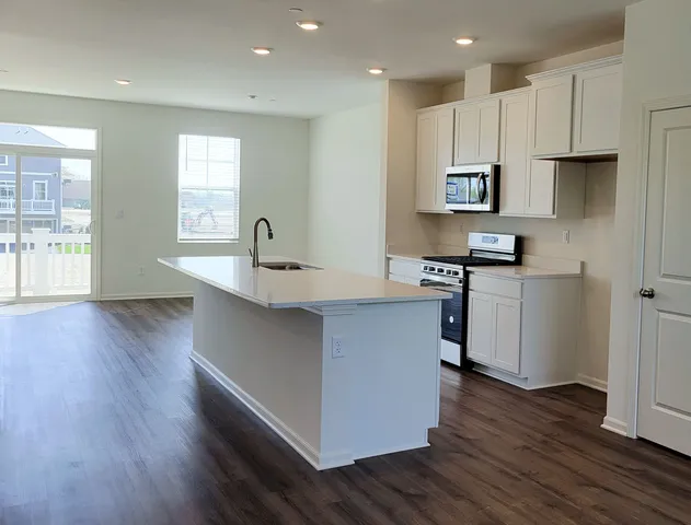 a kitchen with stainless steel appliances granite countertop a sink a stove and a wooden floors