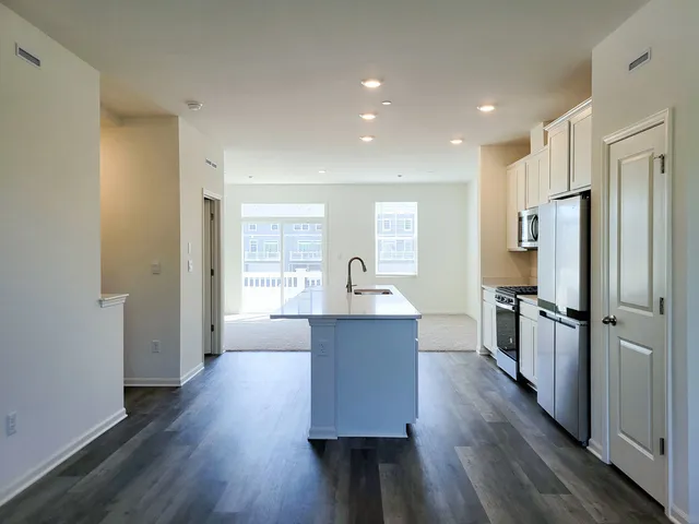 a large kitchen with a center island wooden floor stainless steel appliances and windows