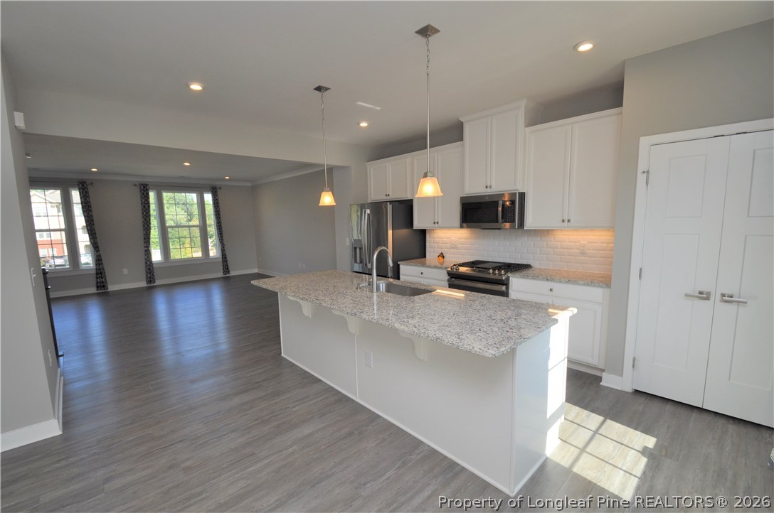 200 Misty Pike Drive Raleigh, NC 27603 - Photo 11 of 49 a large white kitchen with stainless steel appliances granite countertop a stove a sink a refrigerator and a dining table with wooden floor