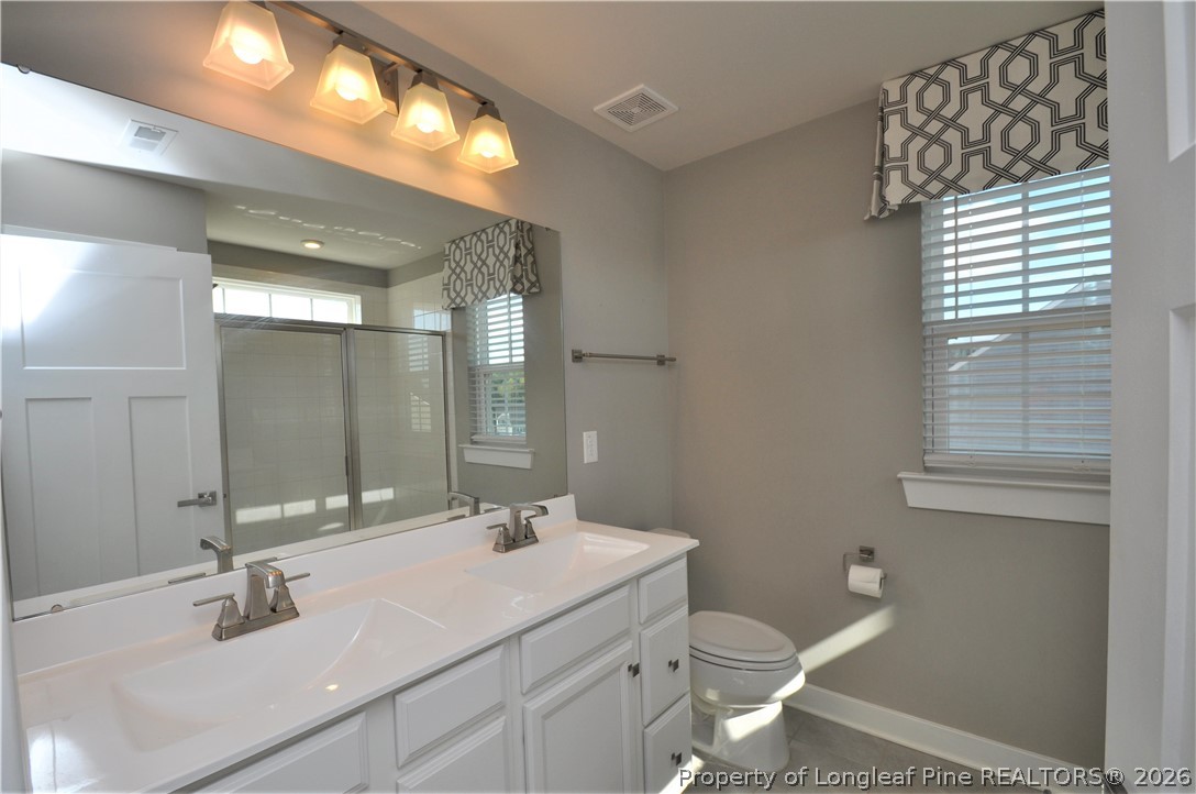 200 Misty Pike Drive Raleigh, NC 27603 - Photo 29 of 49 a bathroom with a double vanity sink toilet and a mirror