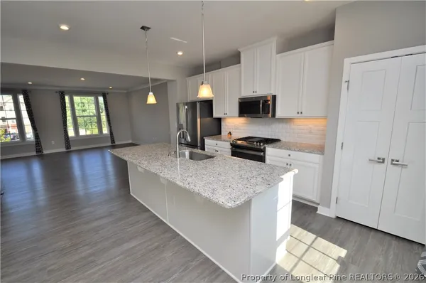a kitchen with stainless steel appliances kitchen island granite countertop a stove a sink and a microwave