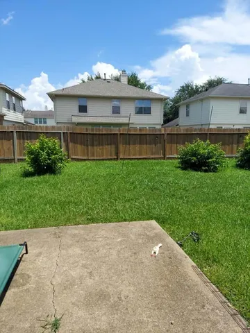 a view of a house next to a big yard and large trees