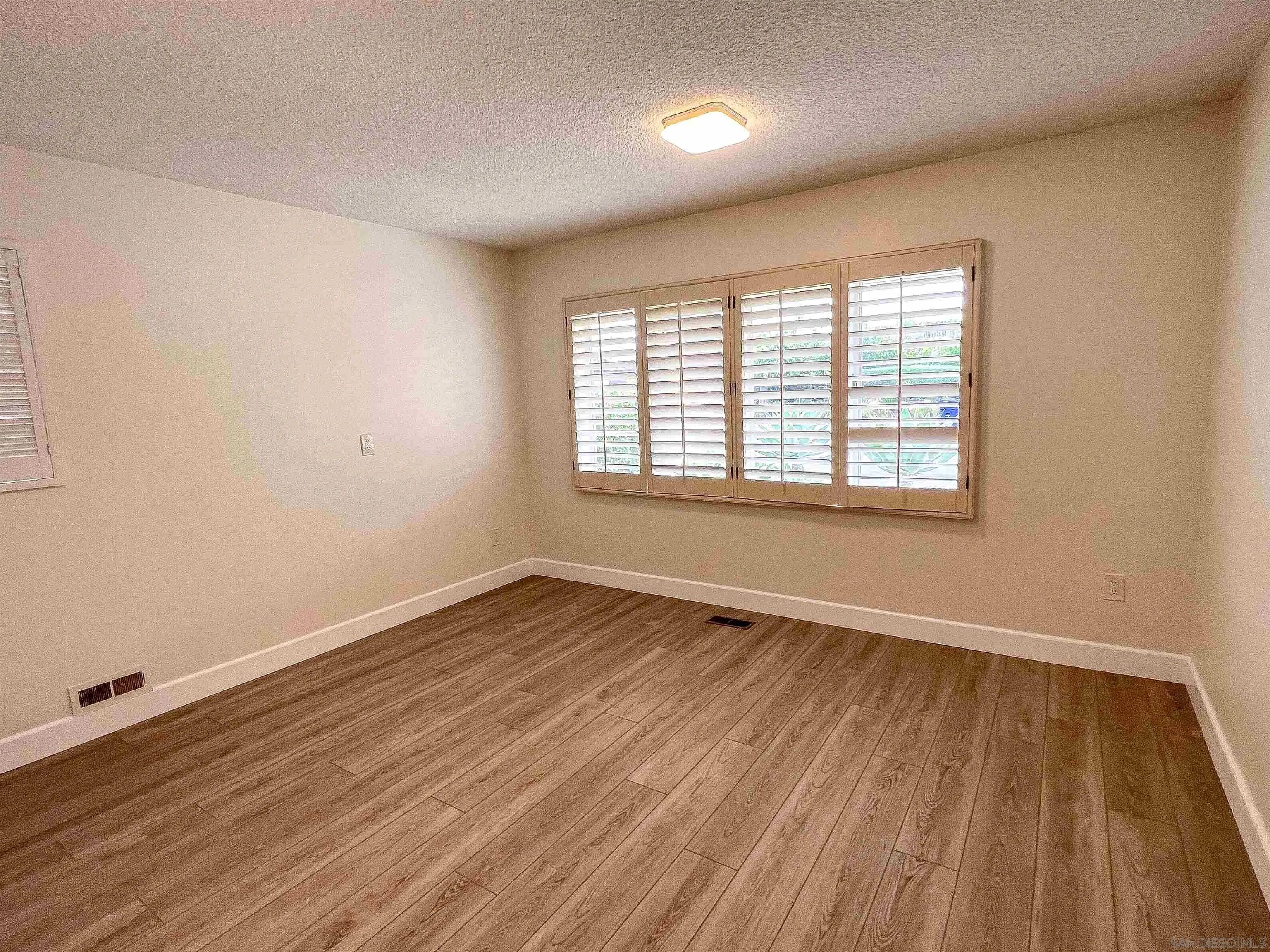 1671 Paseo Bonita La Jolla, CA 92037 - Photo 13 of 17 an empty room with wooden floor and windows