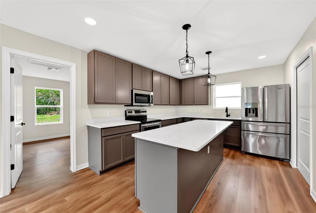607 Thomas Avenue Leesburg, FL 34748 - Photo 8 of 50 a kitchen with stainless steel appliances kitchen island a refrigerator sink and cabinets