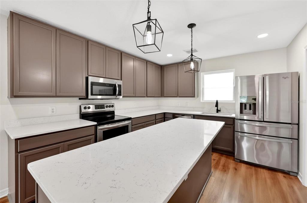 607 Thomas Avenue Leesburg, FL 34748 - Photo 10 of 50 a kitchen with stainless steel appliances a microwave a stove a sink dishwasher a refrigerator and white cabinets with wooden floor