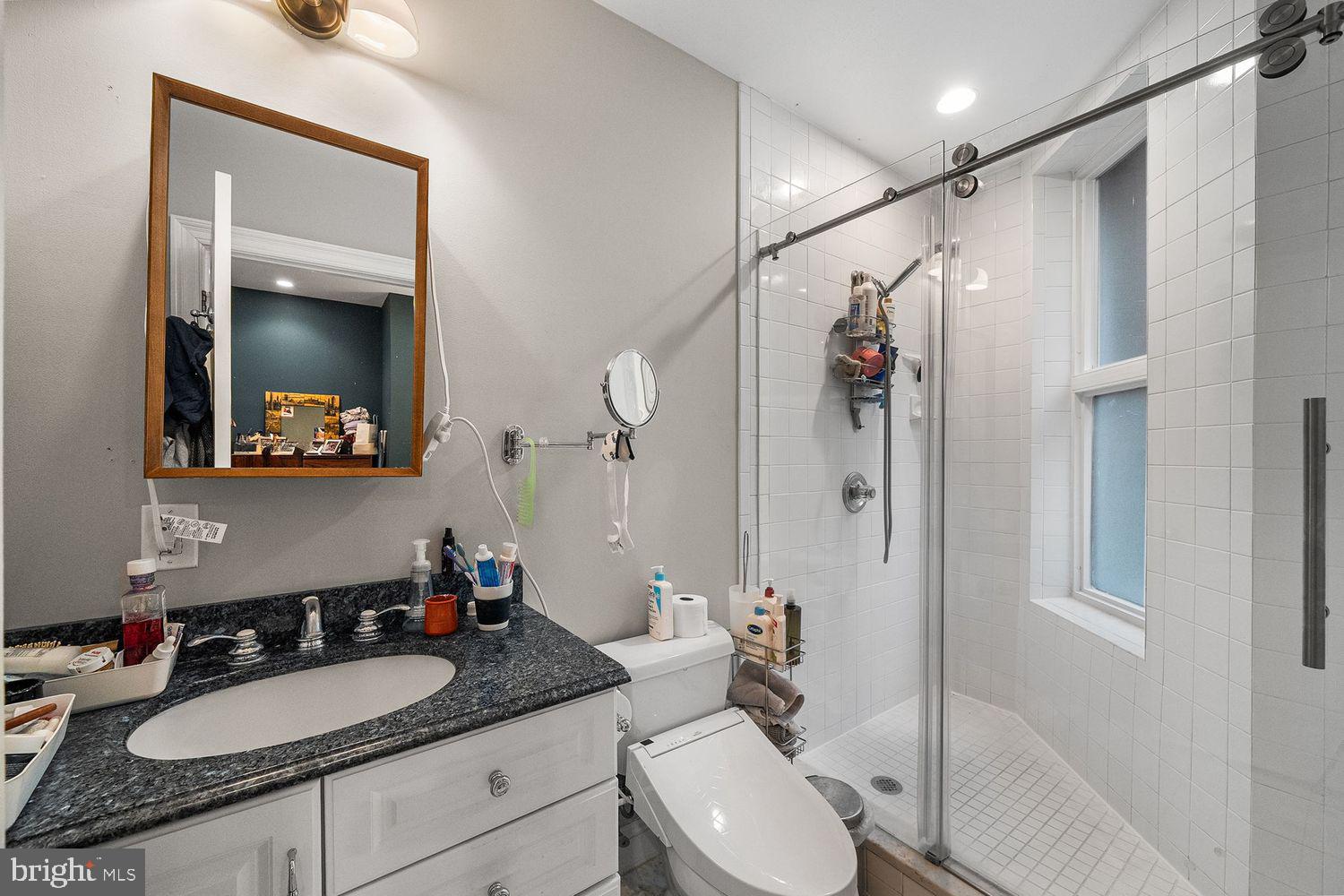 1423 R Street Northwest, Unit 105 Washington, DC 20009 - Photo 19 of 32 a bathroom with a granite countertop sink mirror vanity and toilet