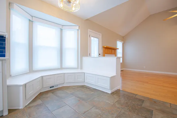 a view of an empty room with window and cabinet area