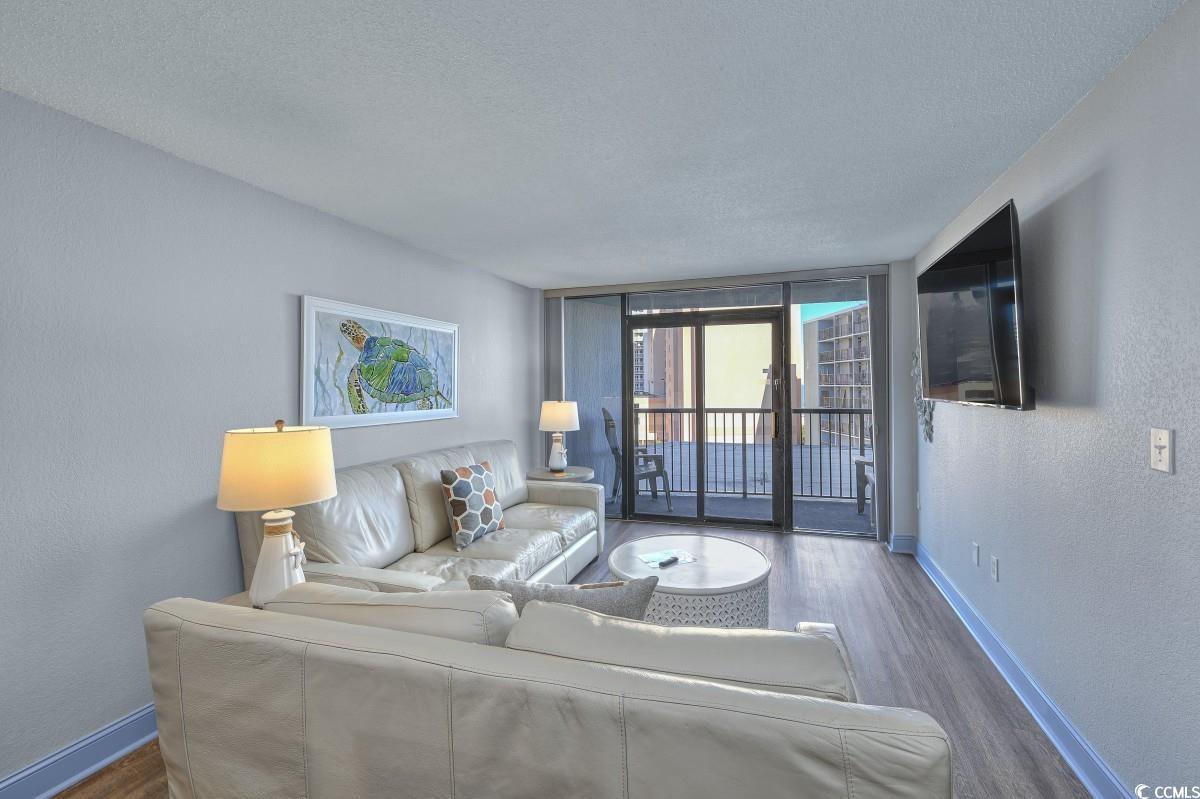 2311 South Ocean Boulevard, Unit 624 Myrtle Beach, SC 29577 - Photo 11 of 28 Living area featuring a textured wall, floor to ceiling windows, wood finished floors, and a textured ceiling