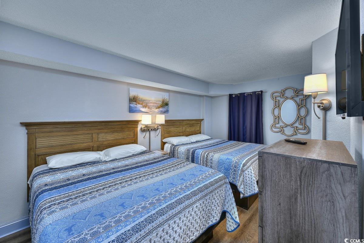 2311 South Ocean Boulevard, Unit 624 Myrtle Beach, SC 29577 - Photo 6 of 28 Bedroom featuring a textured ceiling, wood finished floors and two queen beds.