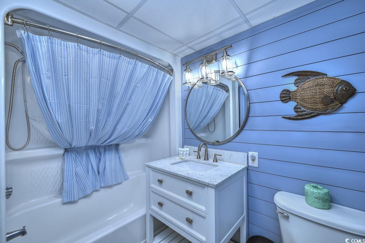2311 South Ocean Boulevard, Unit 624 Myrtle Beach, SC 29577 - Photo 7 of 28 Bathroom featuring shower / bathtub combination with curtain, vanity, a paneled ceiling, and wooden walls