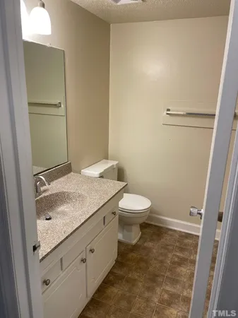 a bathroom with a granite countertop toilet and a sink