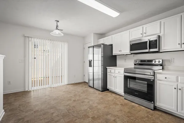 a kitchen with stainless steel appliances granite countertop a refrigerator a stove oven a sink with dishwasher and white cabinets