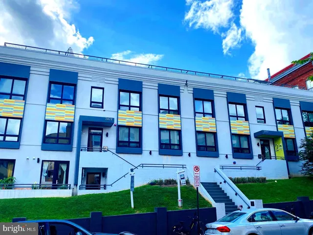a front view of a brick building with many windows and yard