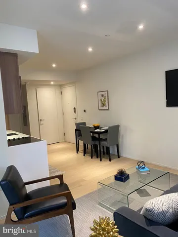 a living room with furniture and a flat screen tv with kitchen view