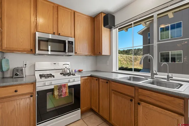 a kitchen with stainless steel appliances granite countertop a refrigerator oven a sink dishwasher and a stove with the view of living room