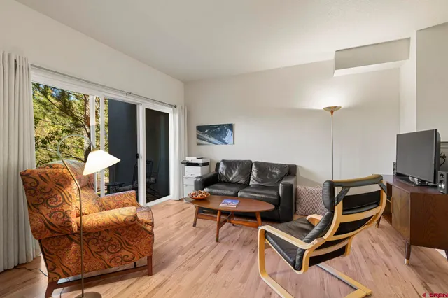 a living room with furniture a flat screen tv and floor to ceiling window