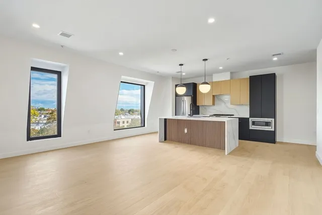 a large kitchen with stainless steel appliances a large counter top a stove and a refrigerator