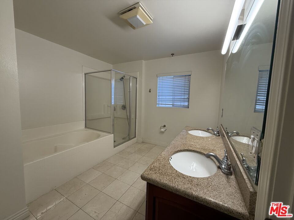 962 Gramercy Drive, Unit 102 Los Angeles, CA 90019 - Photo 15 of 20 a bathroom with a granite countertop sink a mirror and a bathtub