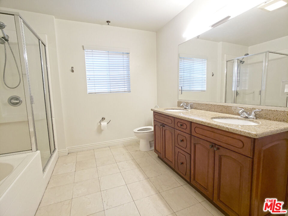 962 Gramercy Drive, Unit 102 Los Angeles, CA 90019 - Photo 7 of 20 a spacious bathroom with a granite countertop sink a mirror a shower and a bathtub