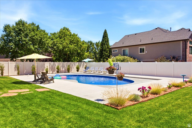2973 West Red Sand Rd Haven Ogden, UT 84401 - Photo 3 of 30 Expansive backyard featuring a curved swimming pool with concrete decking, surrounded by a white privacy fence