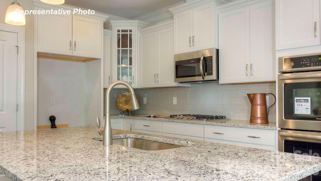 3003 Eclipse Court Indian Trail, NC 28079 - Photo 20 of 48 a kitchen with granite countertop a stove a sink and a microwave