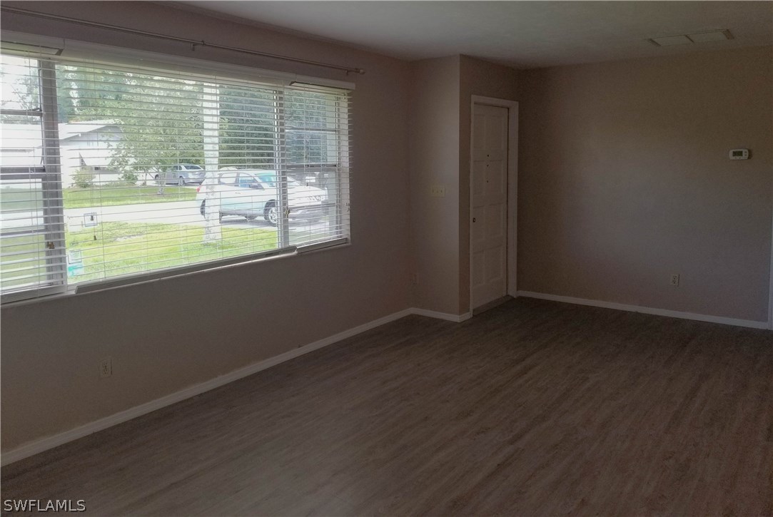 331 Delaware Road Lehigh Acres, FL 33936 - Photo 5 of 22 a view of an empty room with wooden floor and a window