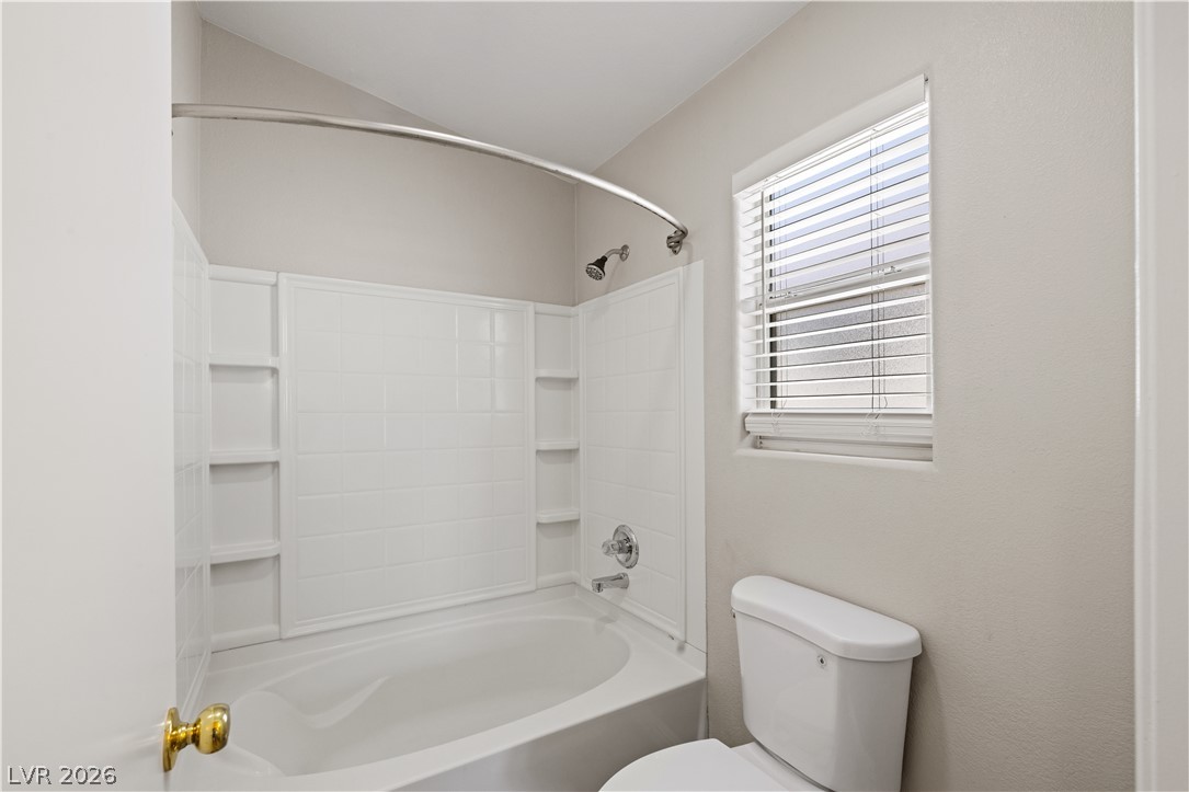 8777 Roping Rodeo Avenue, Unit 101 Las Vegas, NV 89178 - Photo 15 of 25 A well-lit primary bathroom features a shower-tub combo and convenient window for natural illumination.