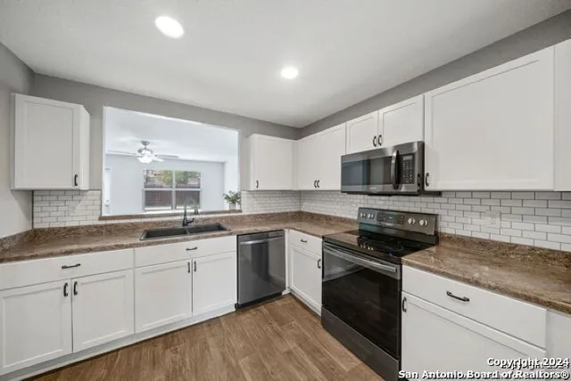 a kitchen with stainless steel appliances granite countertop a stove a sink and white cabinets