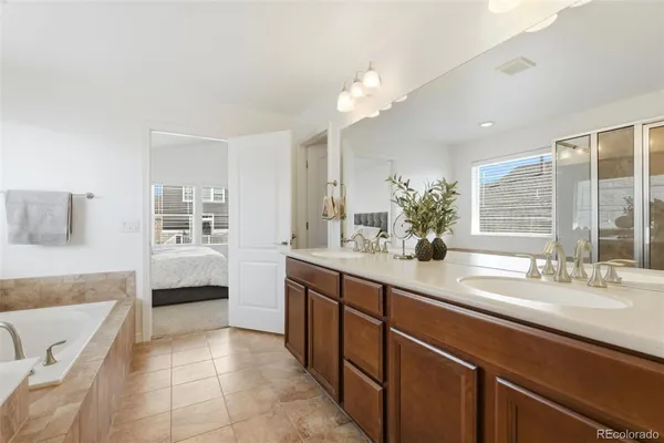 a spacious en suite bathroom with a double vanity sink a tub and mirror