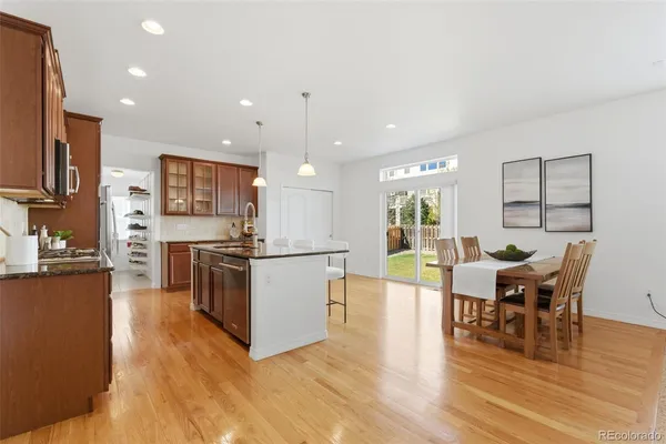 a kitchen with stainless steel appliances kitchen island granite countertop a stove top oven a sink a dining table and chairs