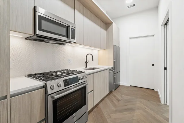 a kitchen with stainless steel appliances granite countertop white cabinets a stove top oven a sink and dishwasher