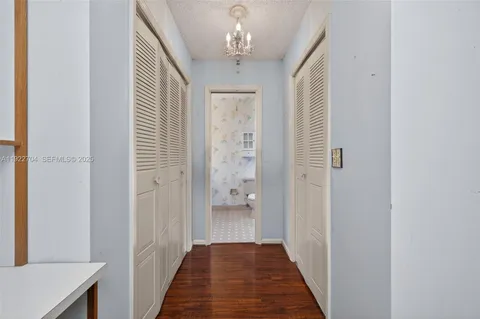 a view of a hallway with wooden floor and chandelier