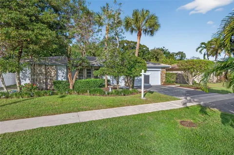 a view of a house with a big yard and palm trees