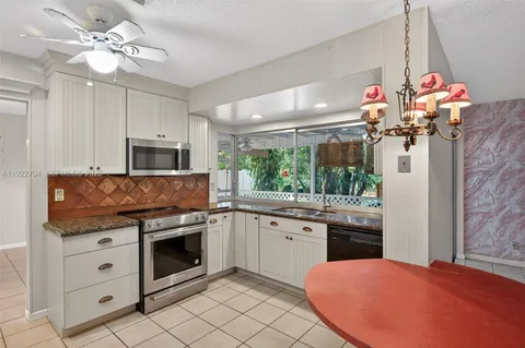a kitchen with granite countertop a sink cabinets stainless steel appliances and a chandelier
