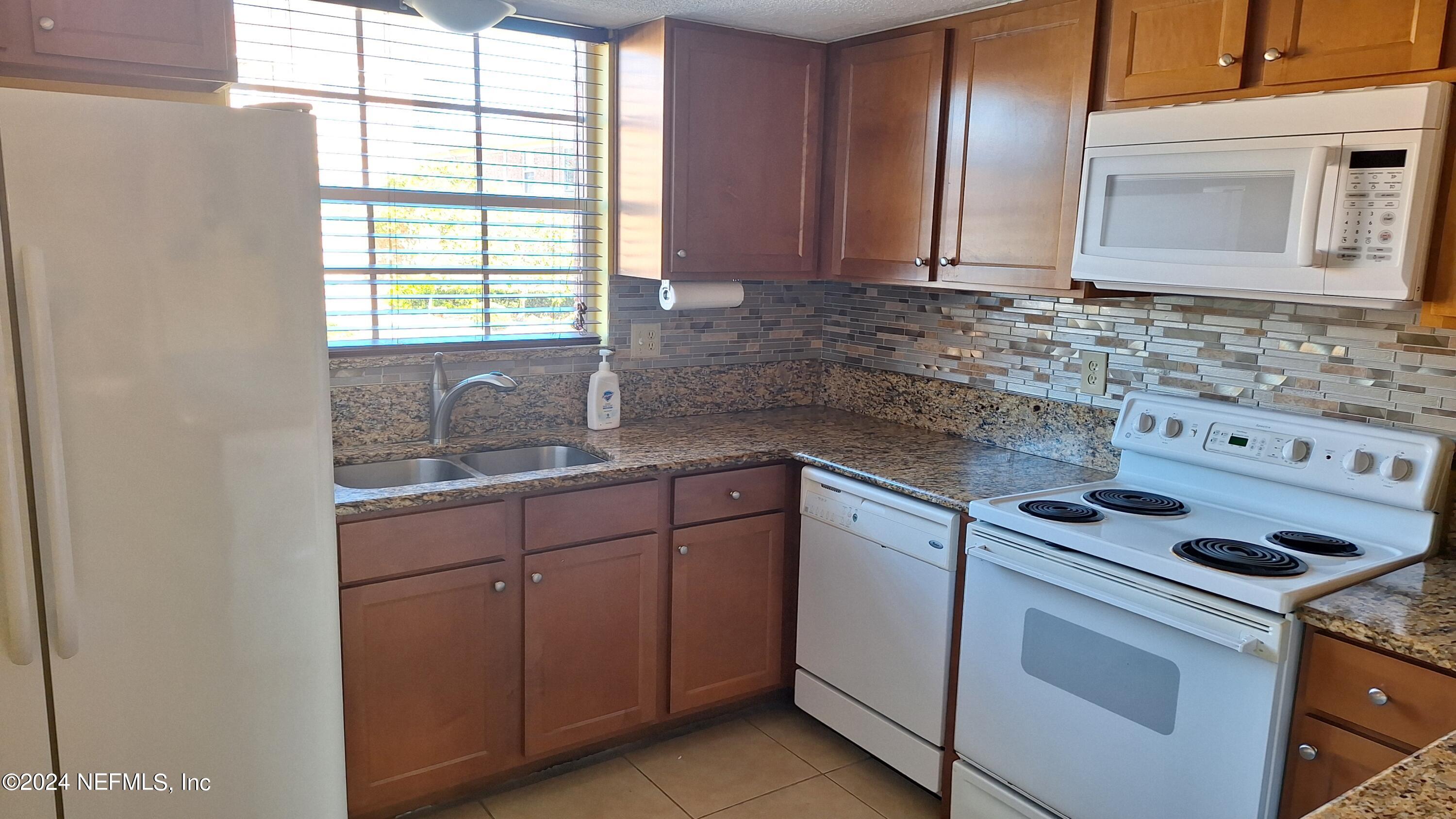 a kitchen with granite countertop cabinets stainless steel appliances a sink and a window
