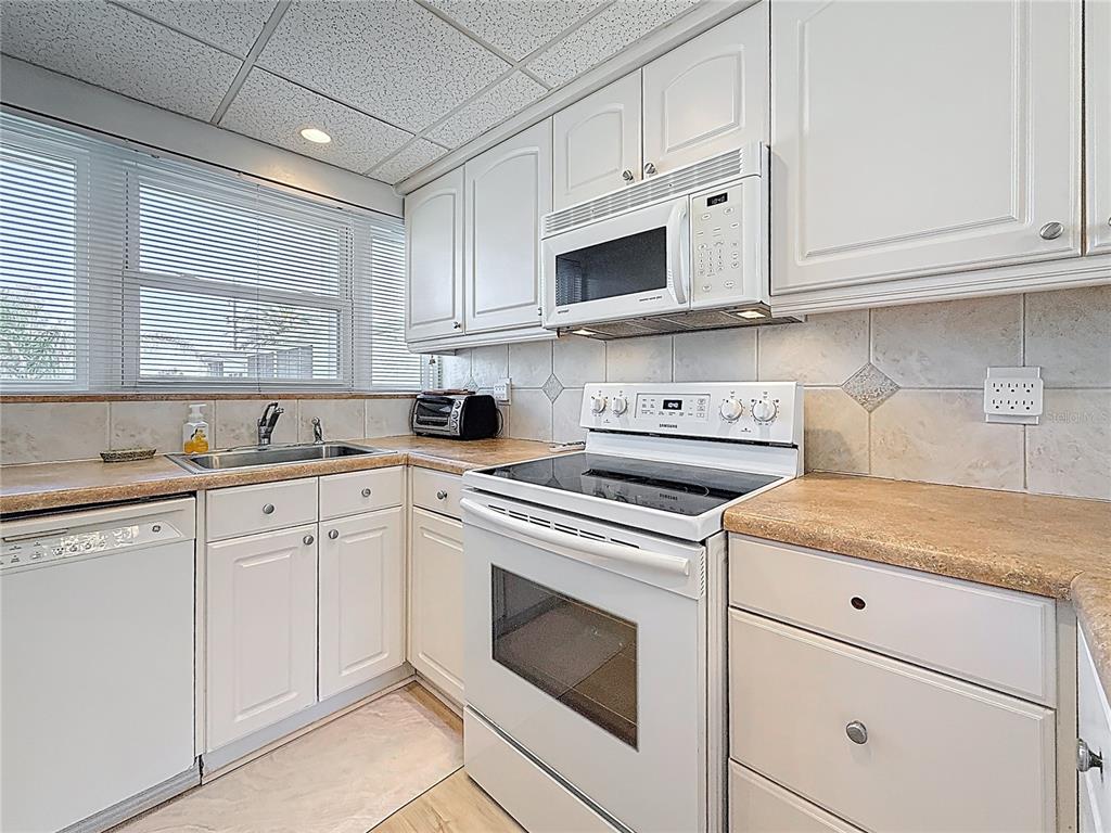 7050 Sunset Way, Unit 22 St. Pete Beach, FL 33706 - Photo 11 of 30 a kitchen with white cabinets stainless steel appliances and sink