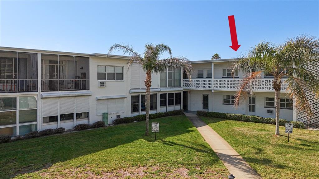 7050 Sunset Way, Unit 22 St. Pete Beach, FL 33706 - Photo 2 of 30 a front view of a house with a yard and swimming pool