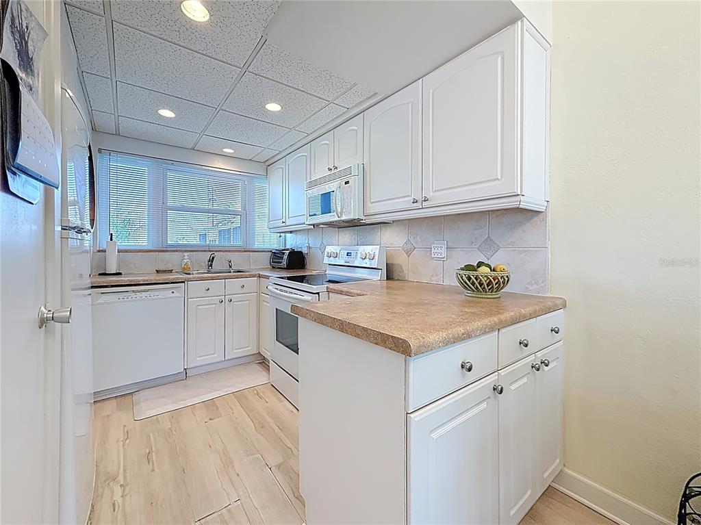 7050 Sunset Way, Unit 22 St. Pete Beach, FL 33706 - Photo 10 of 30 a kitchen with granite countertop white cabinets and white appliances