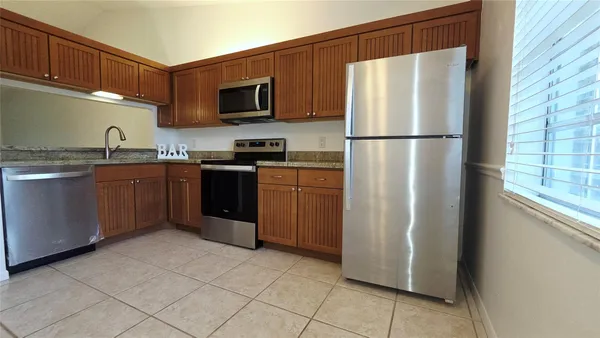 a kitchen with stainless steel appliances granite countertop a refrigerator stove a sink dishwasher and microwave