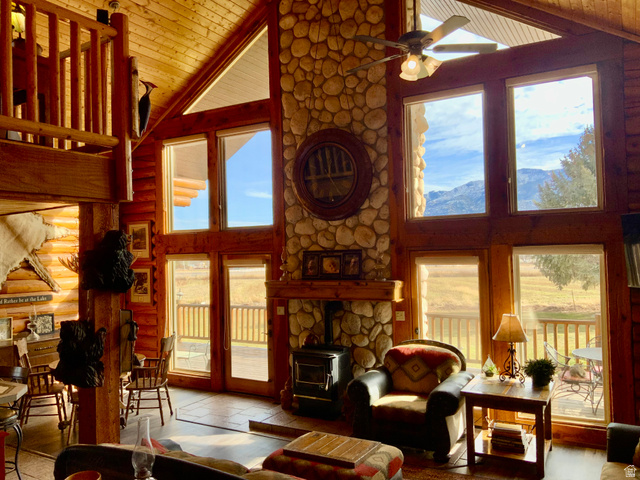 76 Highway 118 Monroe, UT 84754 - Photo 25 of 76 Living area featuring a wood stove, high vaulted ceiling, a ceiling fan, rustic walls, and a wood ceiling with exposed beams