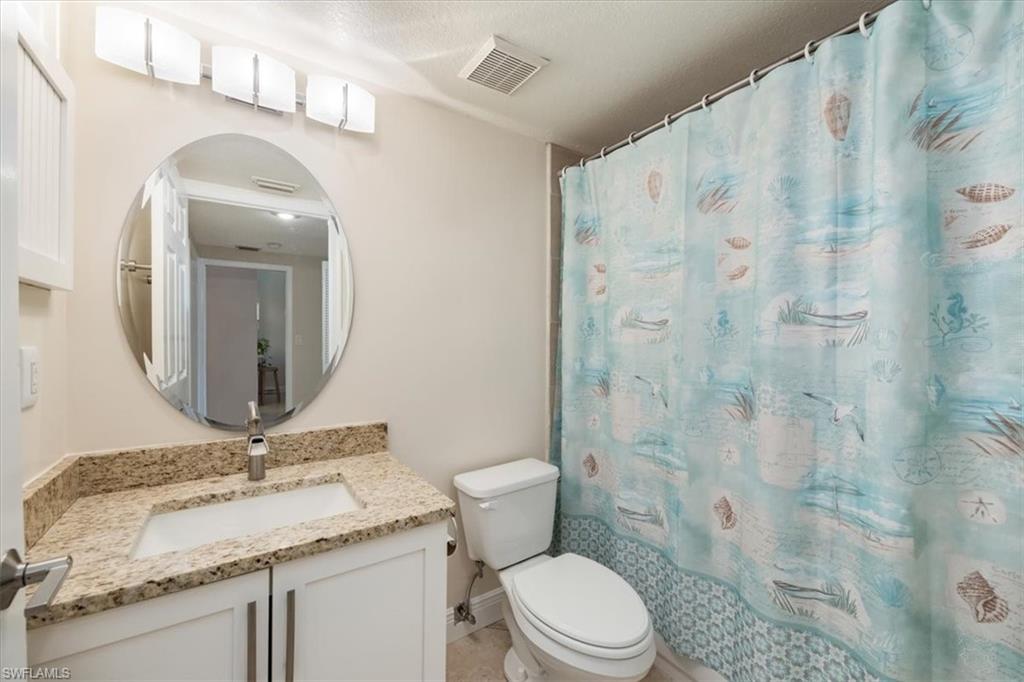 6025 Chardonnay Lane, Unit 103 Naples, FL 34119 - Photo 32 of 45 a bathroom with a granite countertop sink a toilet and a mirror