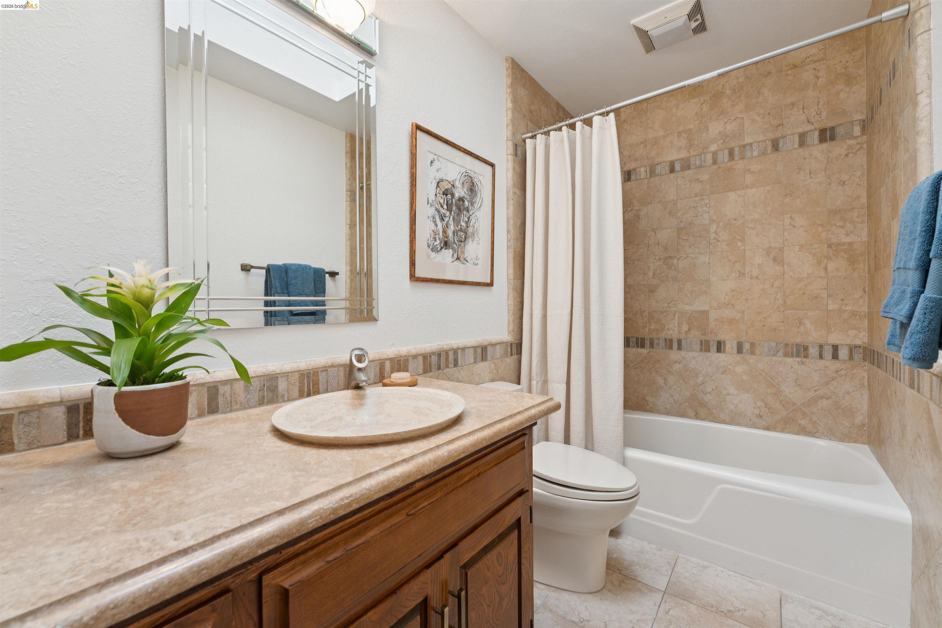 7 Jo Lin Court El Sobrante, CA 94803 - Photo 62 of 99 Bathroom featuring a built-in bathtub with tiled surround, wood-finish vanity with an oval vessel sink, and a framed mirror