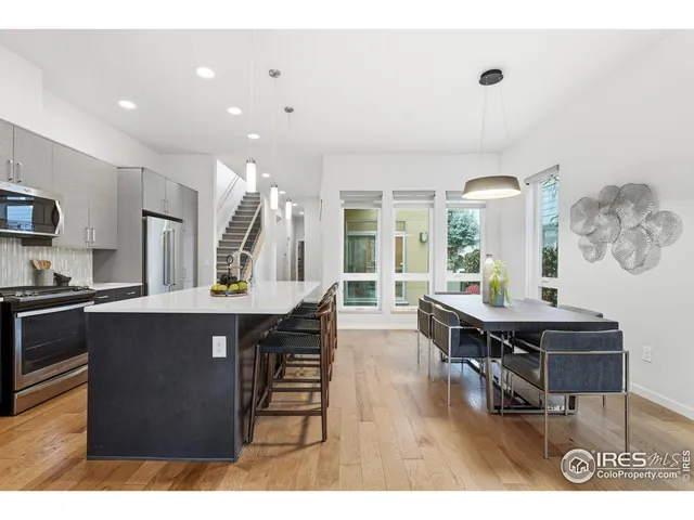 a open kitchen with stainless steel appliances kitchen island granite countertop a table chairs and a refrigerator
