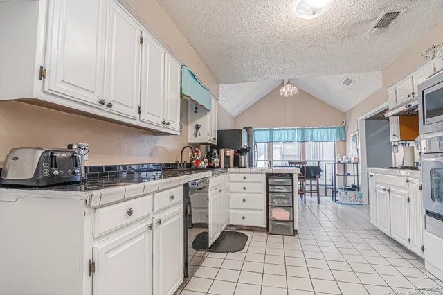 a kitchen with white cabinets and appliances