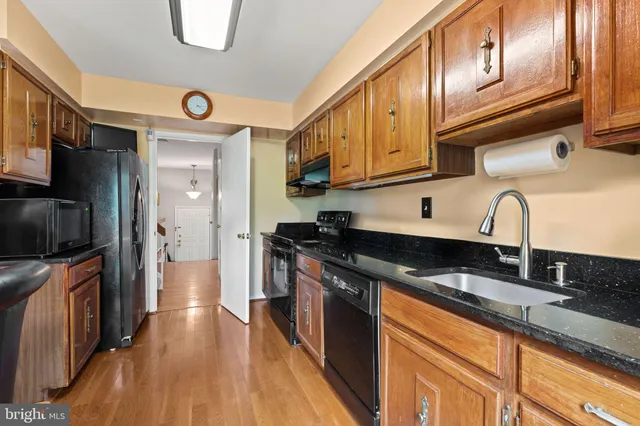 a kitchen with stainless steel appliances granite countertop a sink a stove and a refrigerator
