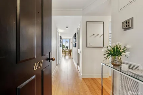 a kitchen with stainless steel appliances granite countertop a stove top oven a refrigerator a dining table and chairs with wooden floor