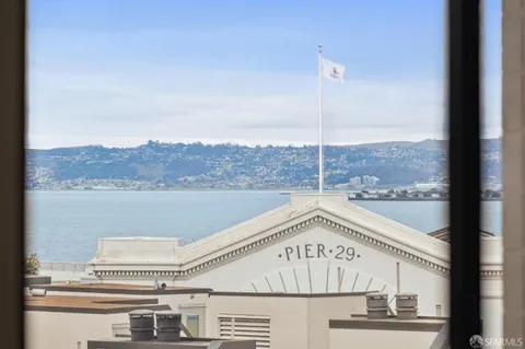 a view of a big room with wooden floor and windows